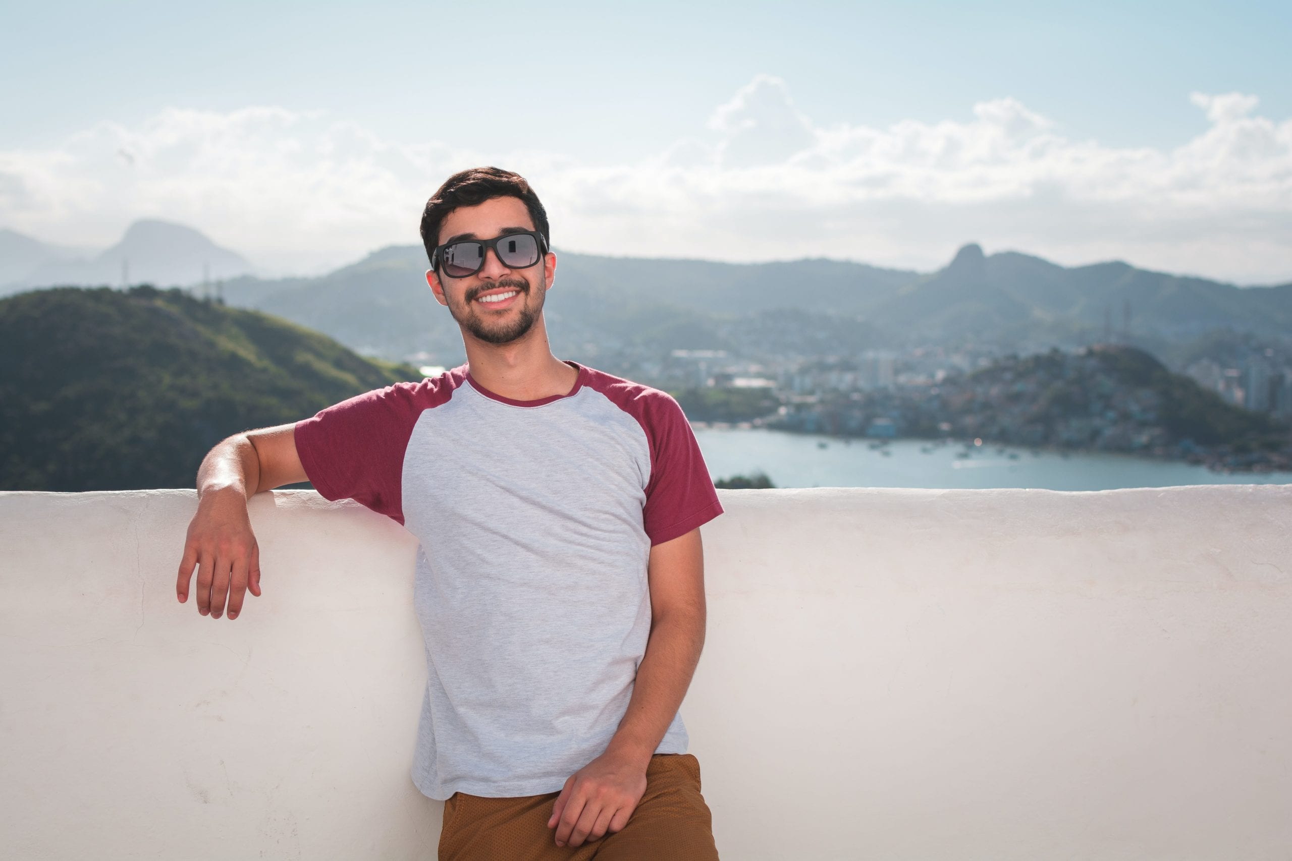 Man smiling who is taking PrEP for HIV standing in front of a mountain view.
